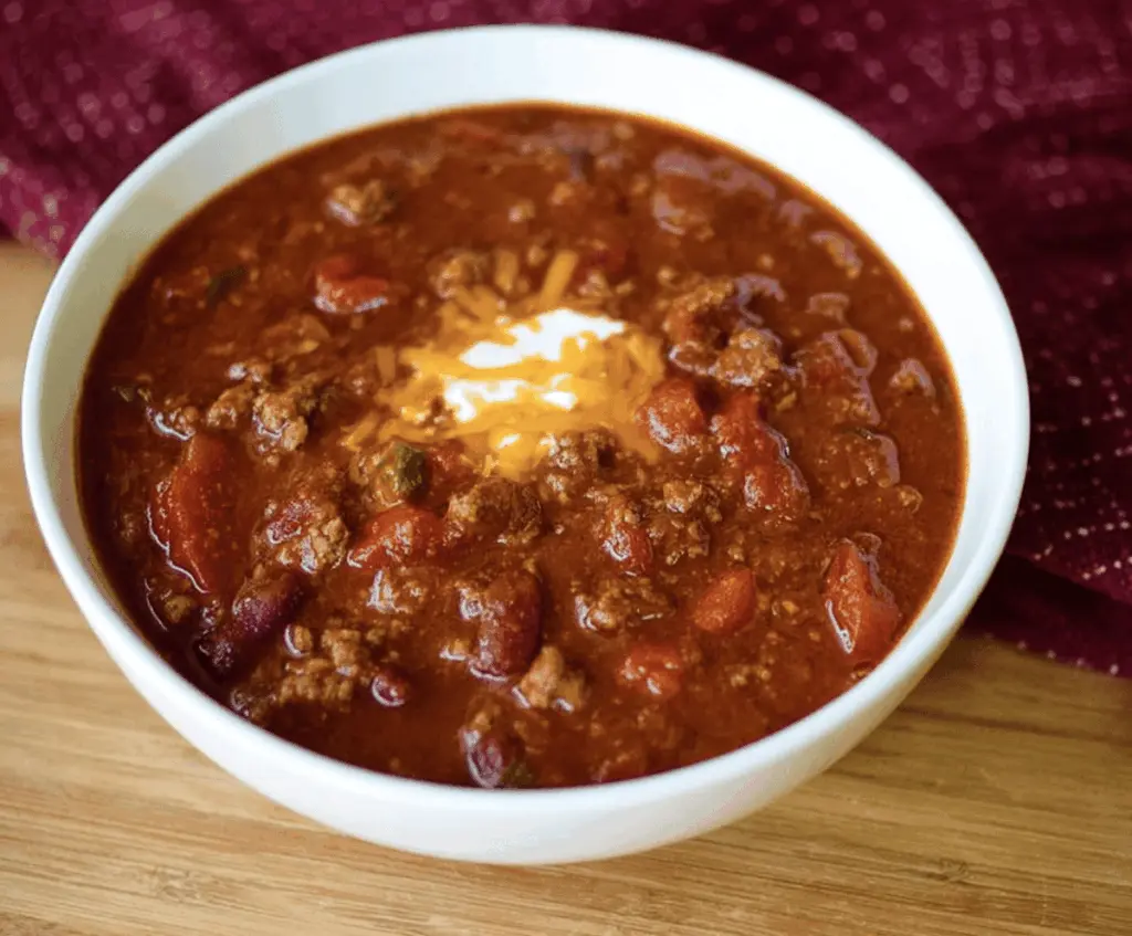 Delicious homemade Copycat Wendy's Chili served in a bowl with toppings on a rustic plate, perfect for a comforting meal.