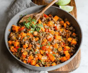 Delicious sweet potato and ground beef skillet with colorful vegetables, topped with fresh herbs, ready to serve