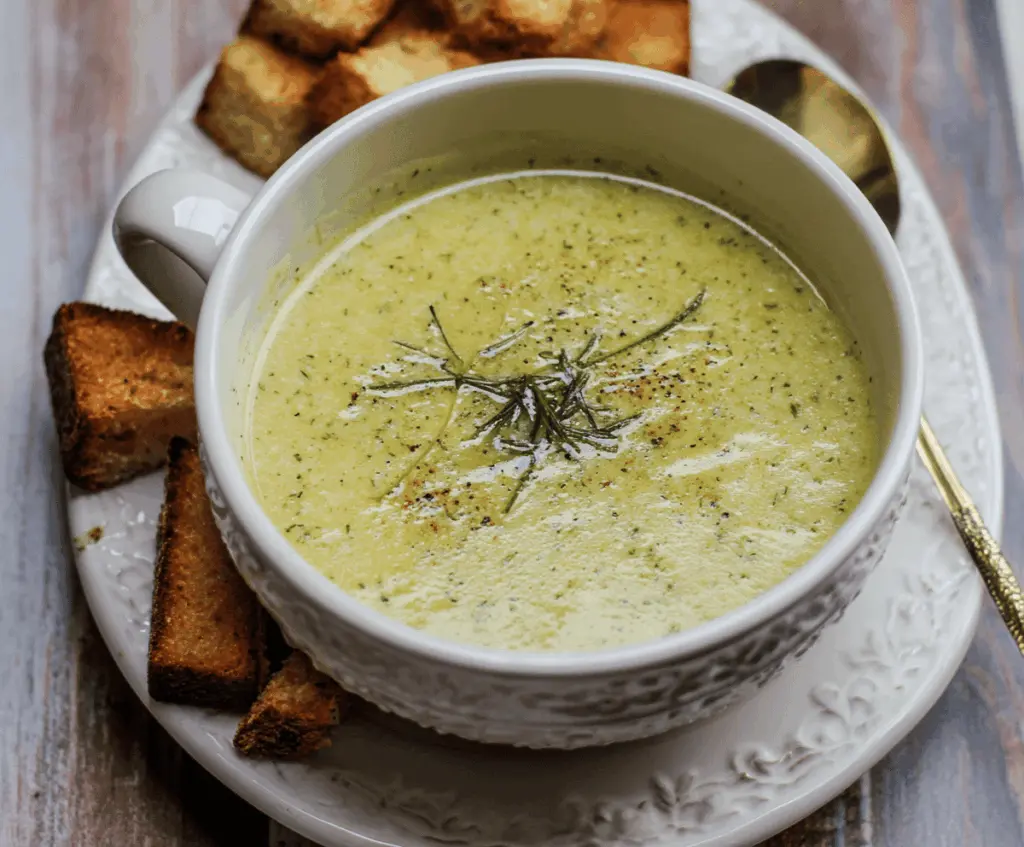 Creamy zucchini soup garnished with fresh herbs and a dollop of sour cream, served in a bowl for a healthy, delicious meal.