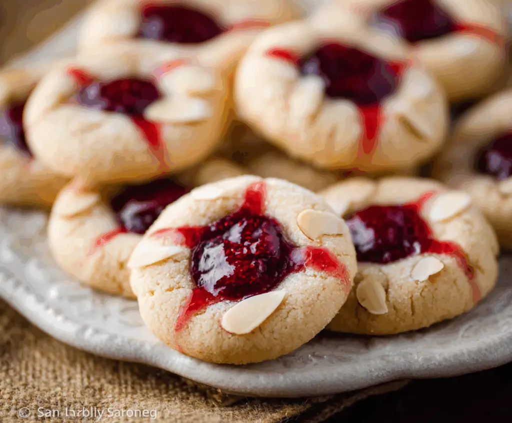 Delicious raspberry almond thumbprint cookies with a golden crust and vibrant raspberry filling.