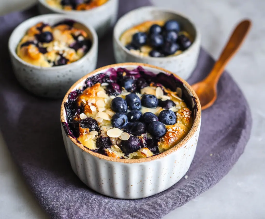 Healthy baked blueberry cottage cheese breakfast bowls served in a white dish with fresh blueberries and mint garnish.