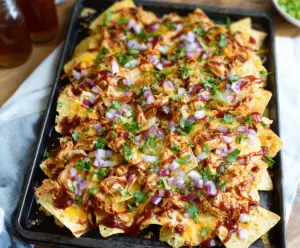 Delicious BBQ Chicken Nachos topped with melted cheese and fresh toppings served on a plate.