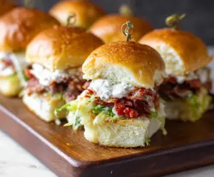 Delicious Italian Grinder Sliders with melted cheese, ham, salami, and fresh vegetables on a platter.