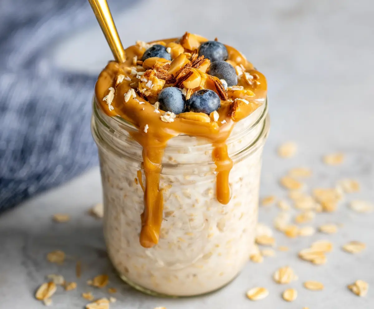 Creamy peanut butter overnight oats in a glass jar with sliced bananas and honey topping