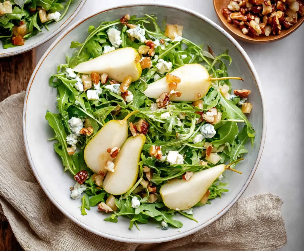 Fresh arugula and sliced pears salad bowl, healthy and colorful meal option.