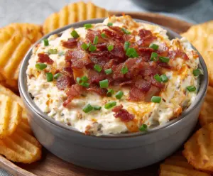 Creamy baked potato dip served in a bowl, topped with chives and cheese, perfect for dipping snacks.