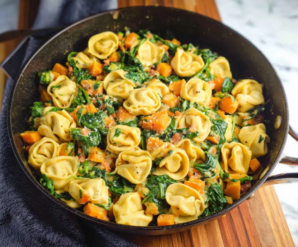 Delicious skillet tortellini with sweet potato and fresh spinach served on a plate.