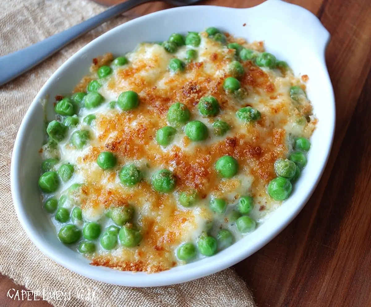 Creamed peas au gratin served in a baking dish with melted cheese and herbs.