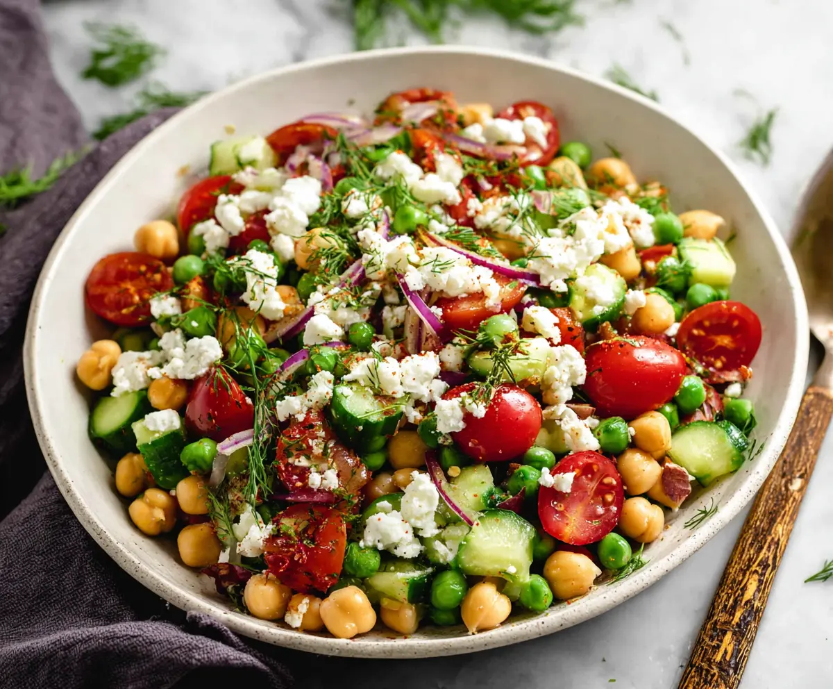 Fresh Mediterranean Pea Salad with cherry tomatoes, feta cheese, and herbs in a bowl.