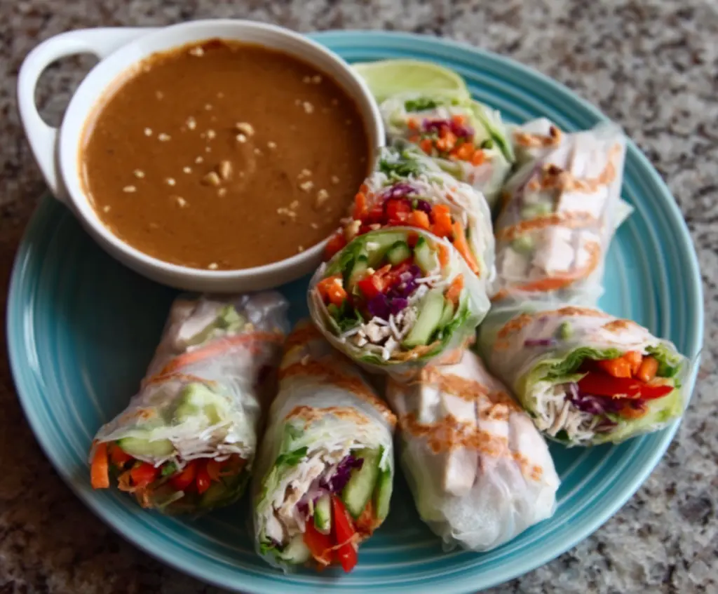 Delicious pork spring rolls served with a flavorful peanut lime dipping sauce on a plate.